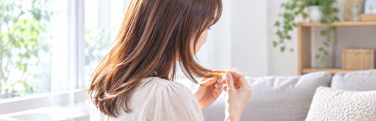色落ちして明るくなったダークブラウン|オレンジブラウンの毛先を確認する女性
