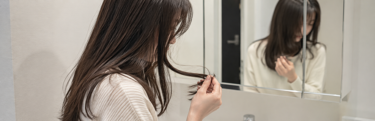 ブリーチしていない暗めの茶髪で毛先を確かめている様子