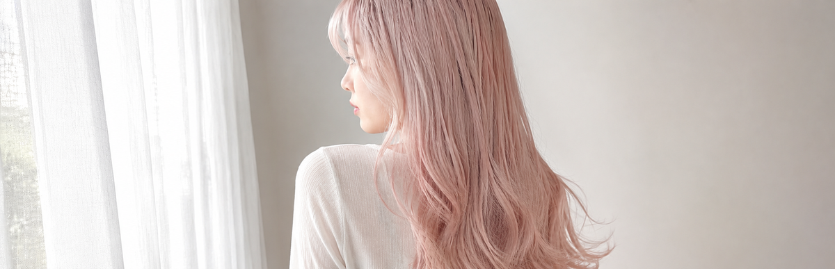 淡い薄ピンクのハイトーンヘアを窓際で後ろから見た様子