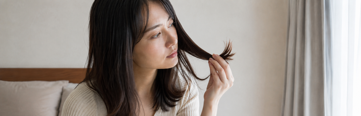 ブリーチしていない暗めの茶髪で毛先を確かめている様子
