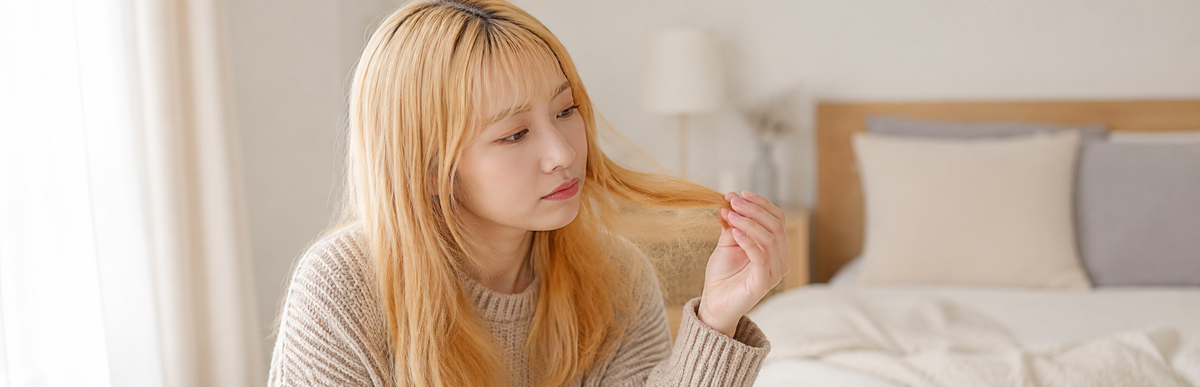 黄ばみの強い明るい金髪で毛先を確かめている様子