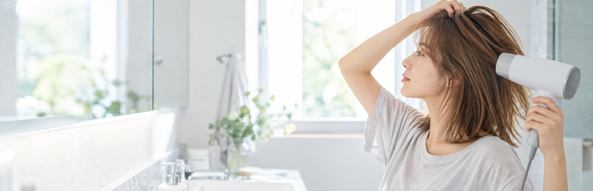美容院に行く日の朝、ドライヤーで髪を乾かす女性