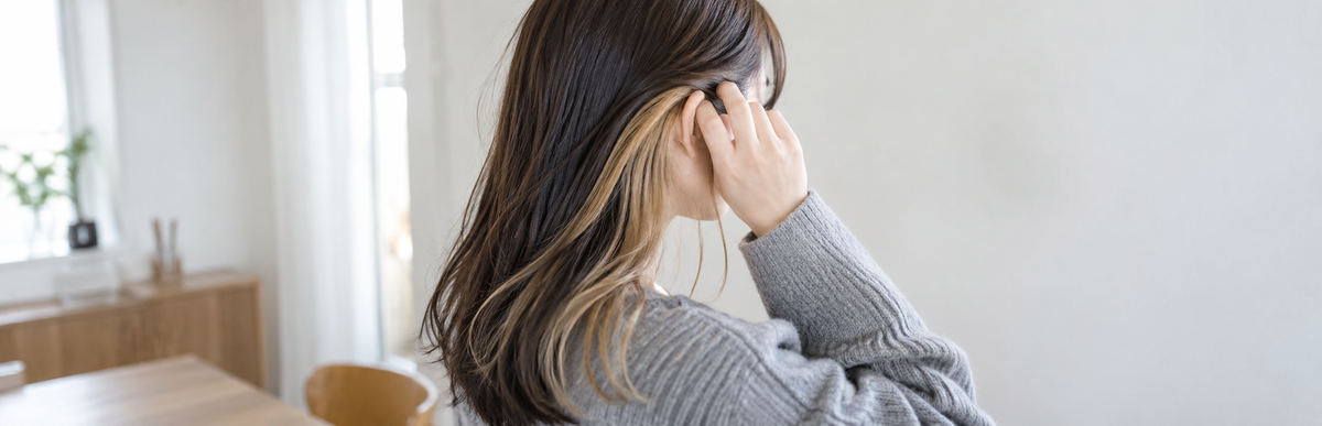 髪を耳にかけて内側のインナーカラーが明るくなっているのが見えている様子