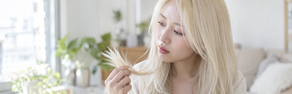 白っぽい金髪まで明るくした髪で毛先を確かめている様子