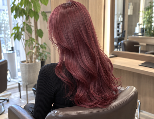美容室でカラーをした直後の、ピンクが少し混ざったチェリーレッドのロングヘアの後ろ姿